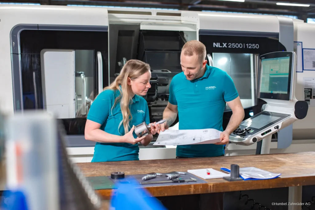 Humbel engineering and production staff review a drawing and a turned part at a CNC lathe
